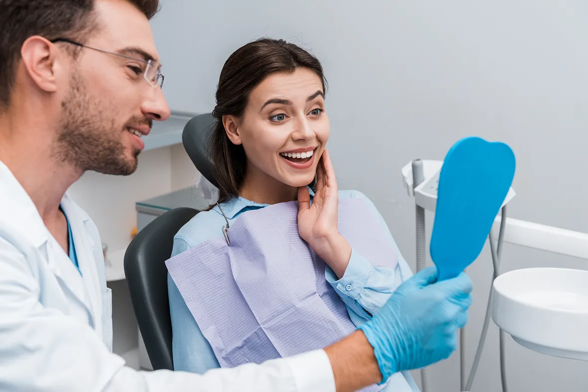 A woman sitting in a dentist chair with a toothbrush in her hand.