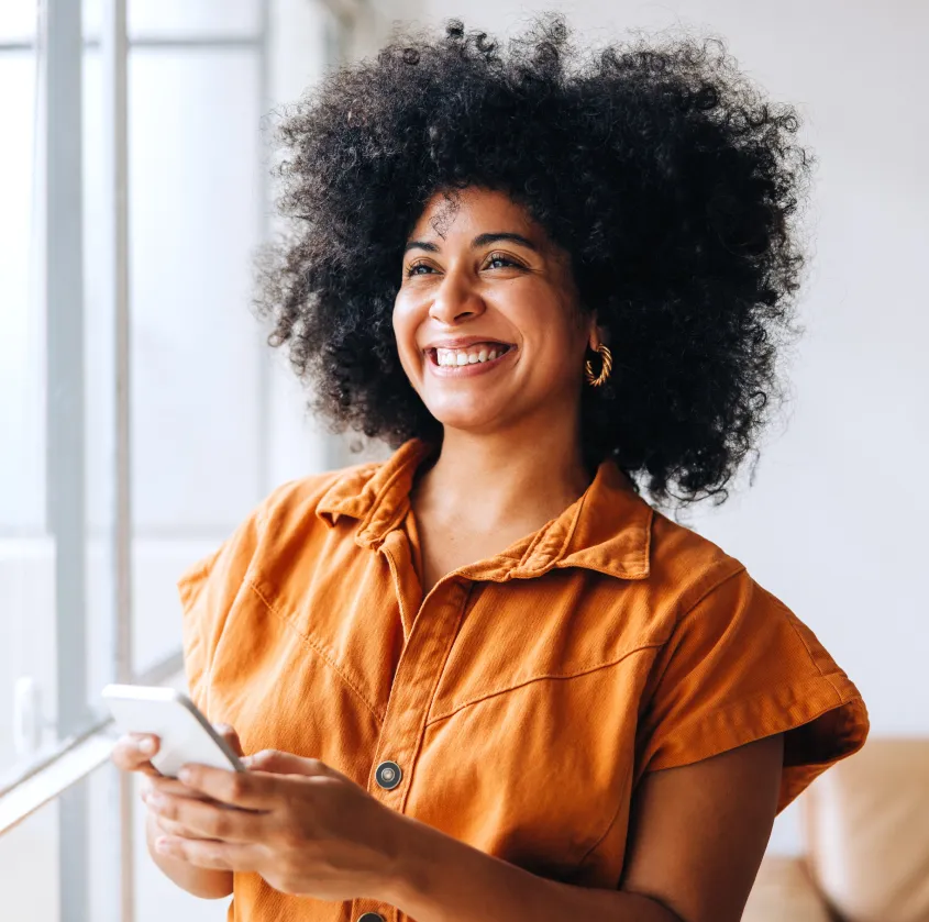 A woman smiling while looking at her cell phone.