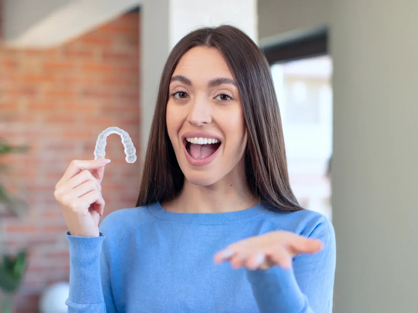 A woman holding a toothbrush in her right hand.