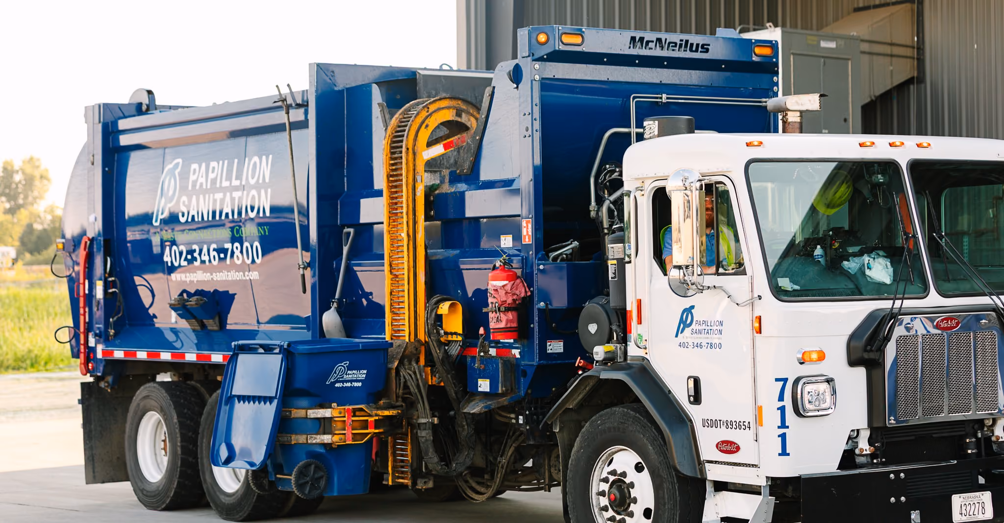 Side-load waste truck providing curbside trash collection service
