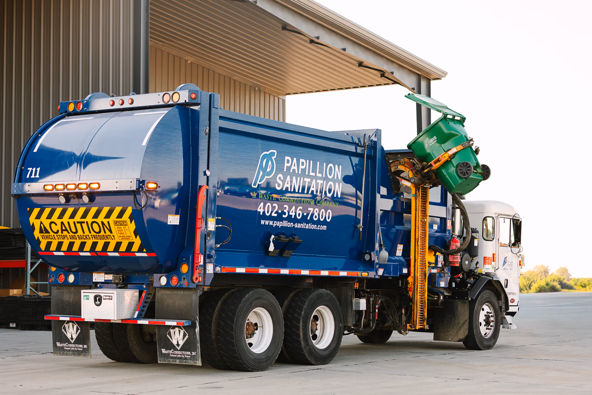 Residential side-load recycling truck collecting materials from a curbside recycling cart