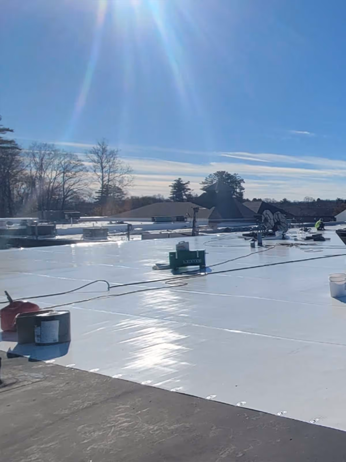 White roof installation on a sunny winter day with work equipment