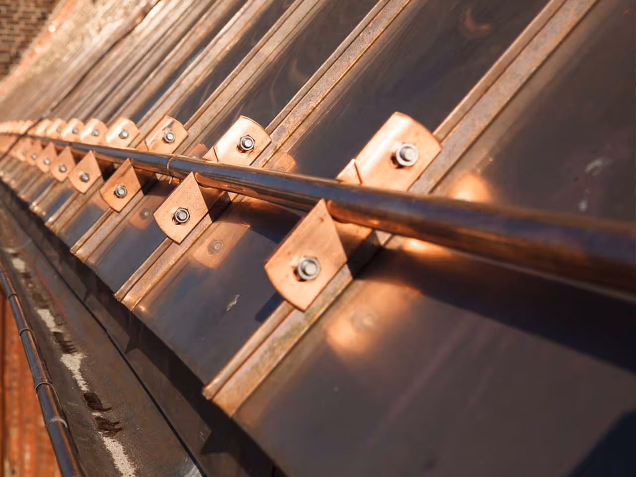 Close-up of a copper metal roof with fastened panels and a central rail.