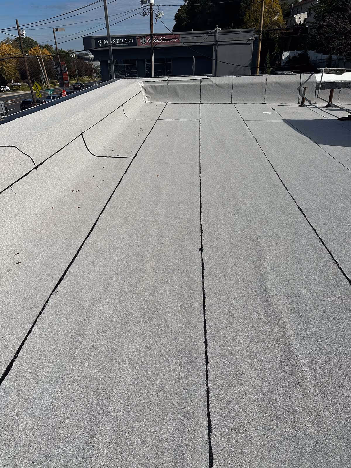 Flat commercial rooftop with light gray roofing material and visible seams.