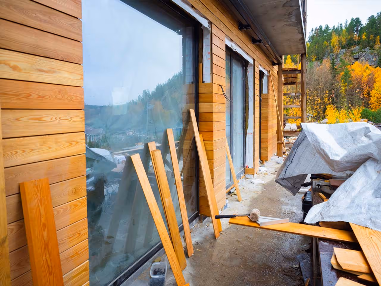Wooden siding installation in progress on a building exterior with tools and wooden planks nearby.