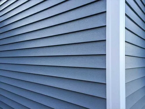 Close-up view of blue vinyl siding on a building corner with white trim.