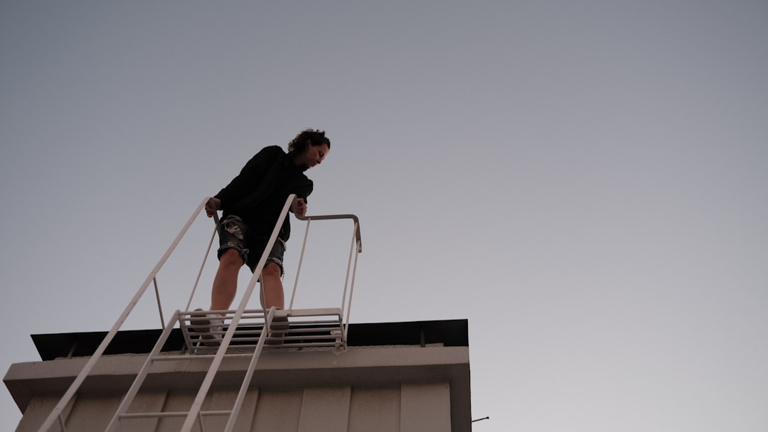 professional installer on a ladder for a multi-story home - gutter downspout installation cost