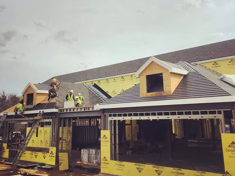 Residential roofing installation in progress on large home exterior