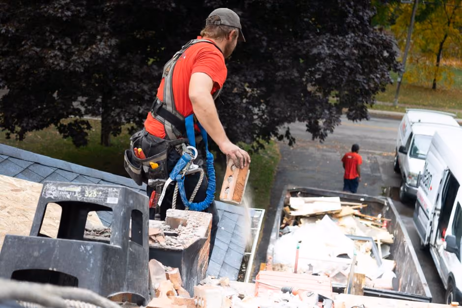 A professional roofing team wearing full safety gear and OSHA-compliant harnesses on a Long Island job site
