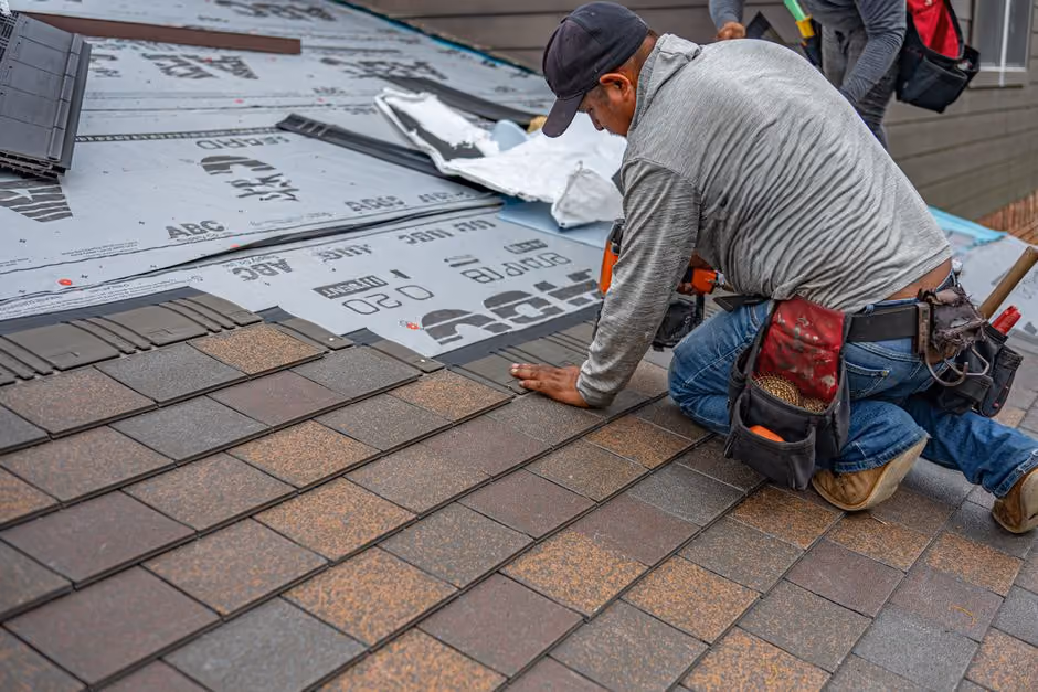 professional roofer repairing shingles on a steep roof professional roofer repairing shingles on a steep roof