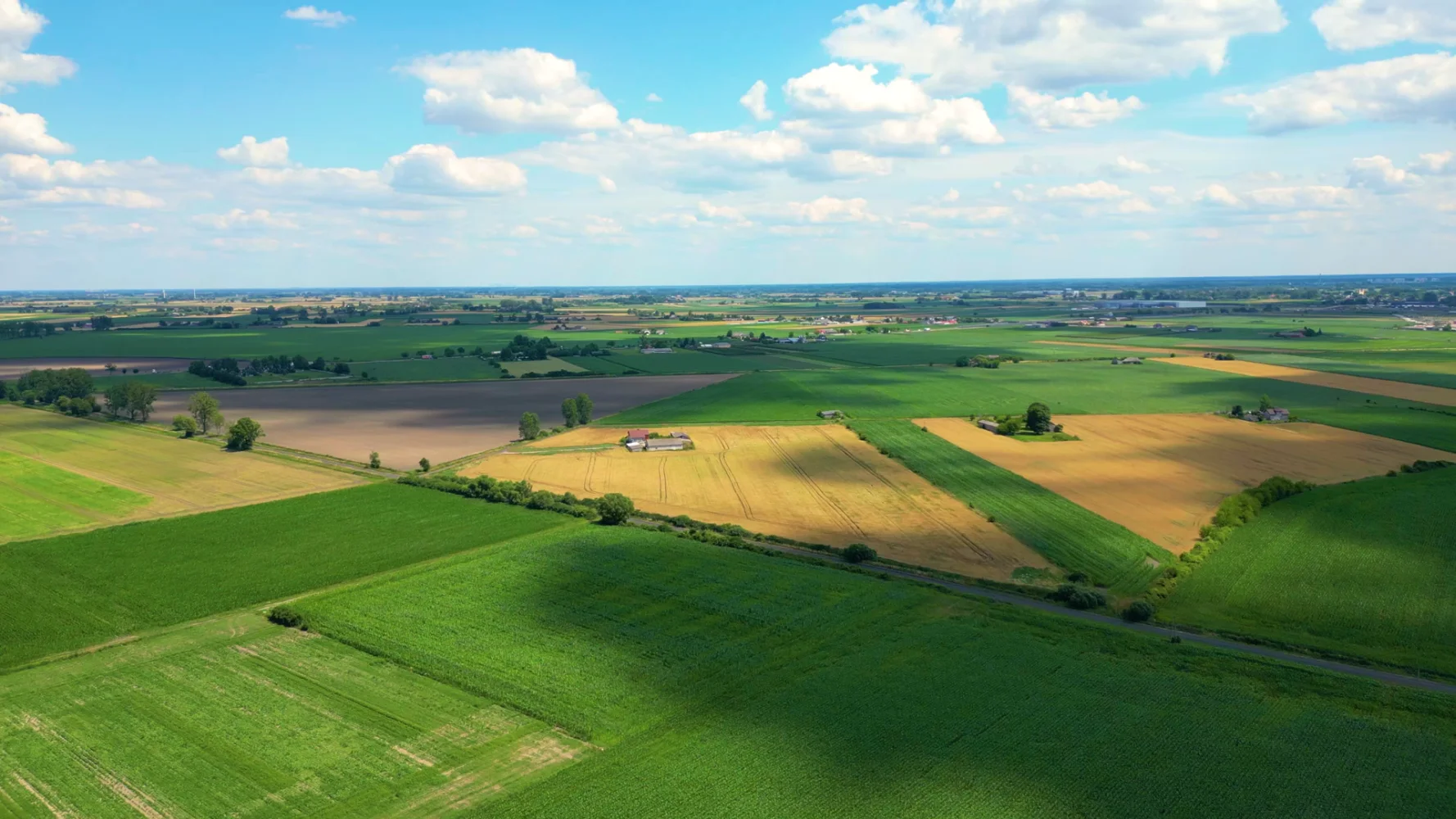 Aerial view of farmland stretching to the horizon under a partly cloudy sky