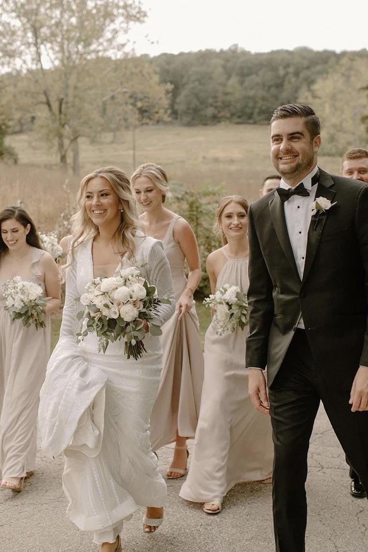Bride and groom walking with their bridal party in soft neutral tones at a countryside wedding planned by Porch & Pearls