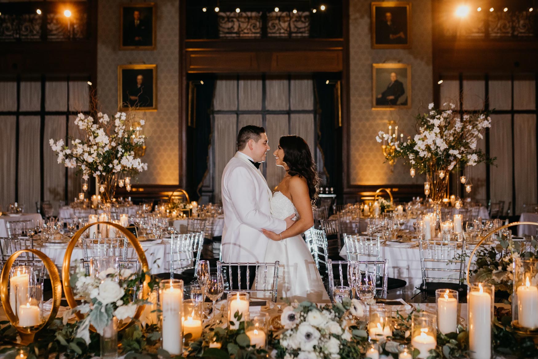 Bride and groom sharing a moment in a candlelit ballroom wedding reception with romantic floral decor