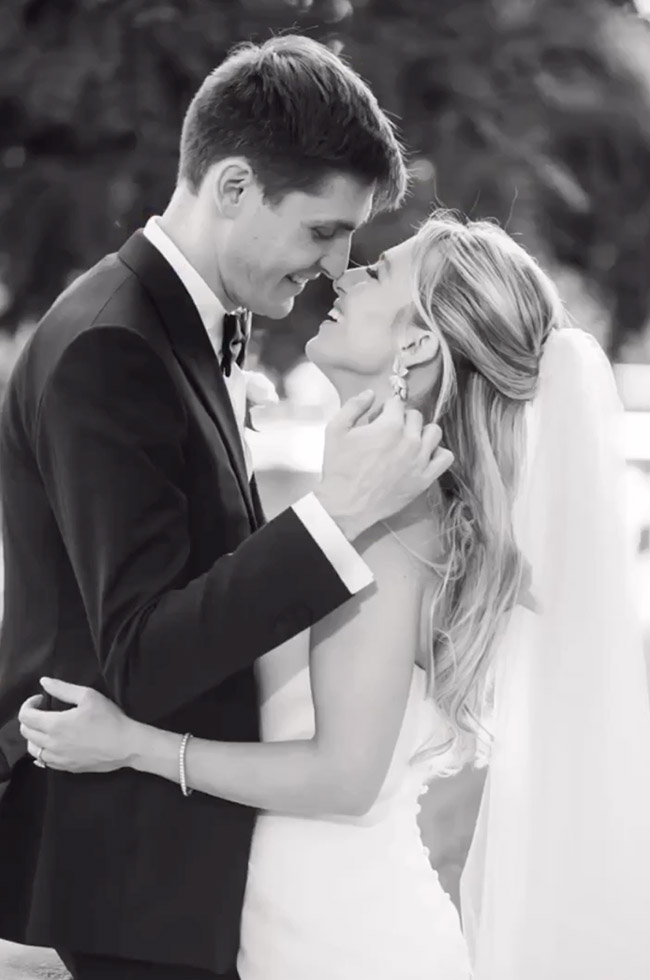 Bride and groom embrace in a romantic black and white portrait, sharing an intimate forehead touch and joyful smiles.