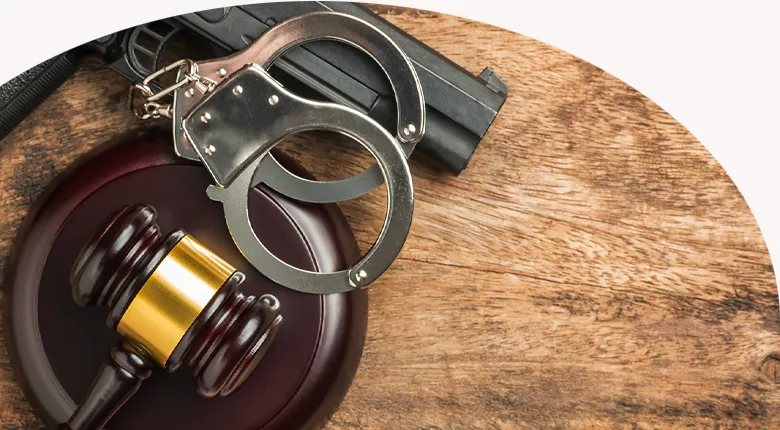 picture of a gun, handcuffs laying on top of a judges gavel