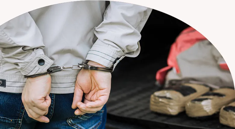 picture of someone being handcuffed with drugs in the background