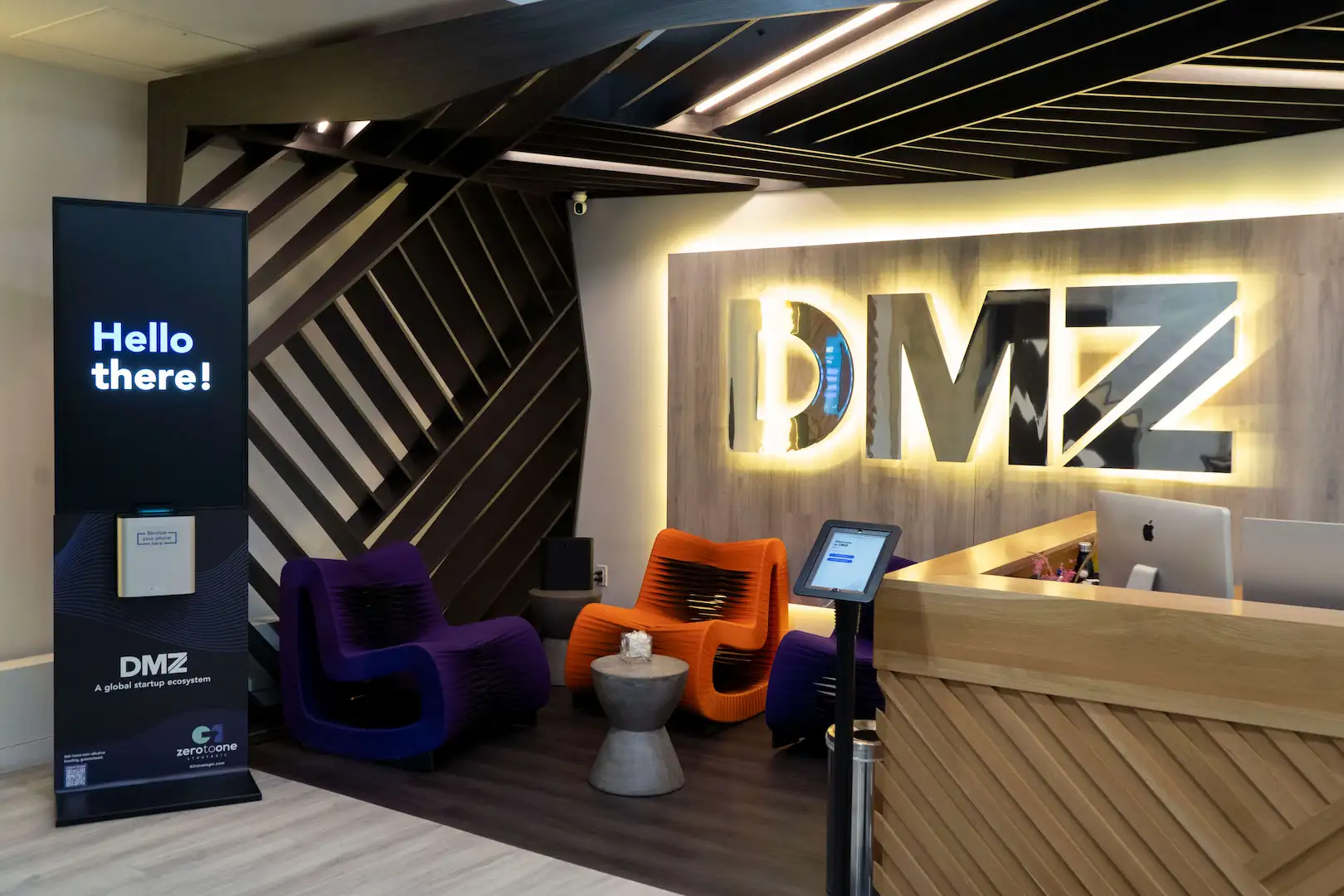 odern lounge area inside DMZ CoWork featuring colorful seating and branded lighting.