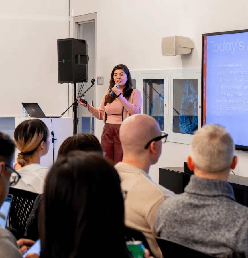 Female speaker presenting to a room of aspiring entrepreneurs at a DMZ workshop, representing hands-on training programs designed to develop real-world startup skills and leadership mindsets.