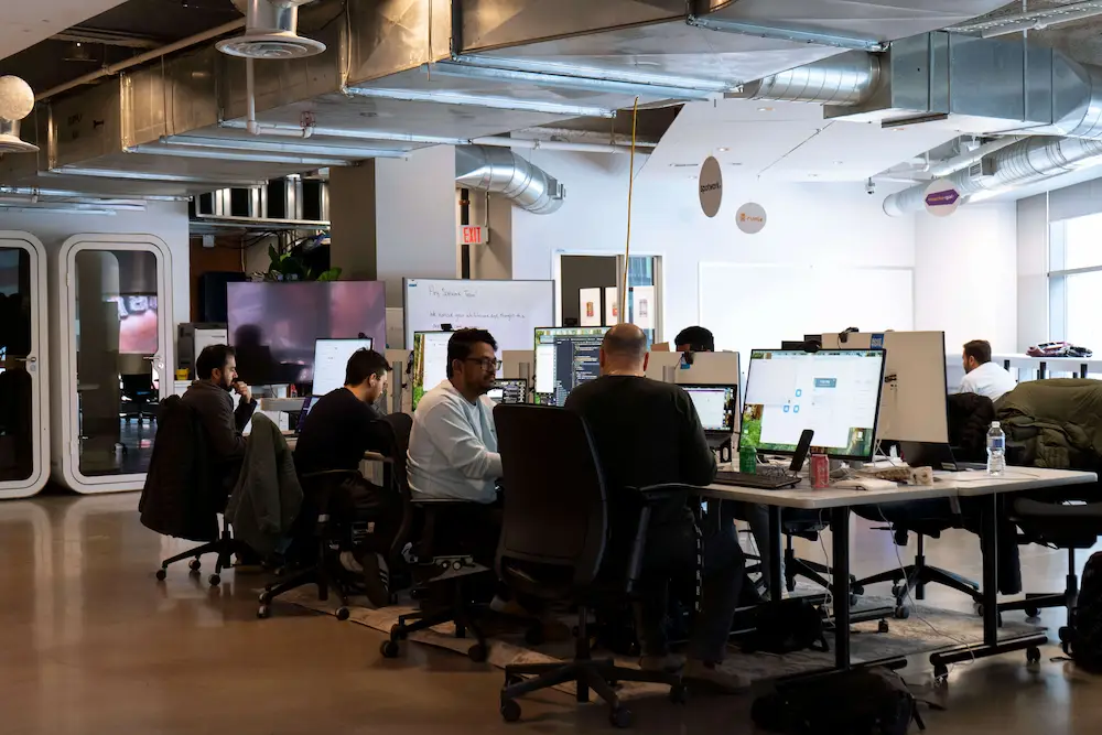 Open-concept coworking space at DMZ CoWork with founders working at desks.