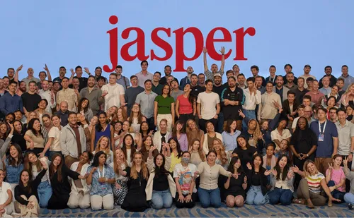 Large diverse group of people posing and smiling in front of a blue background with the red word ‘jasper’ above them.