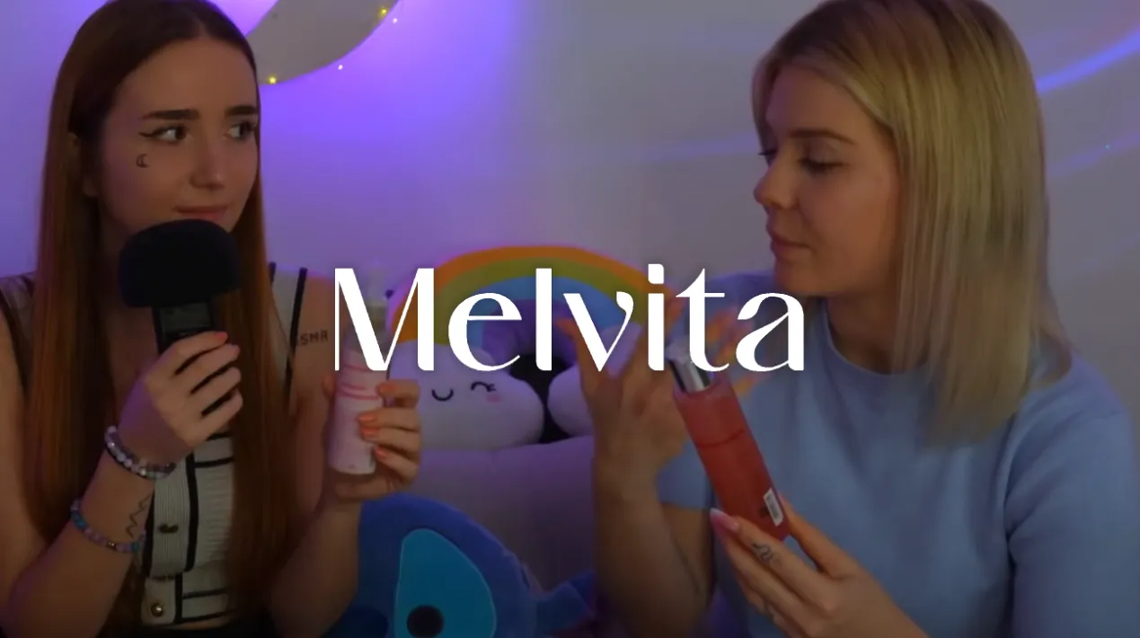 Deux femmes discutent de produits cosmétiques Melvita dans une ambiance tamisée avec des lumières violettes.