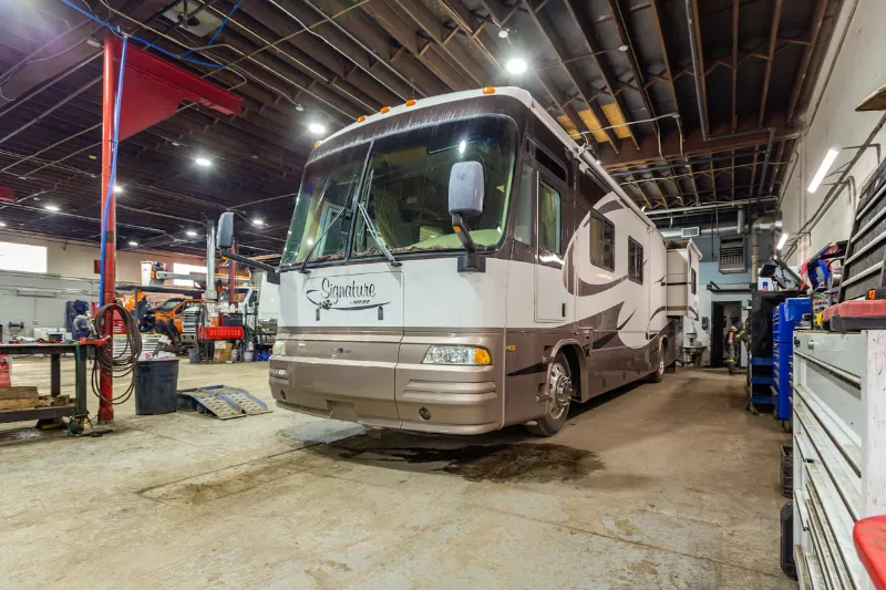 RV repair service on a Signature motorhome parked inside a heavy-duty maintenance shop.