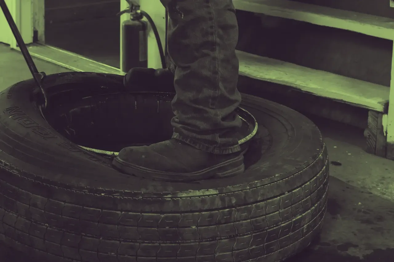Tire service on a heavy-duty truck tire as a technician performs maintenance and inspection in a commercial repair shop.