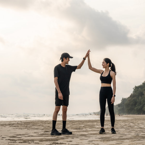 An athletic couple high-fiving on the beach