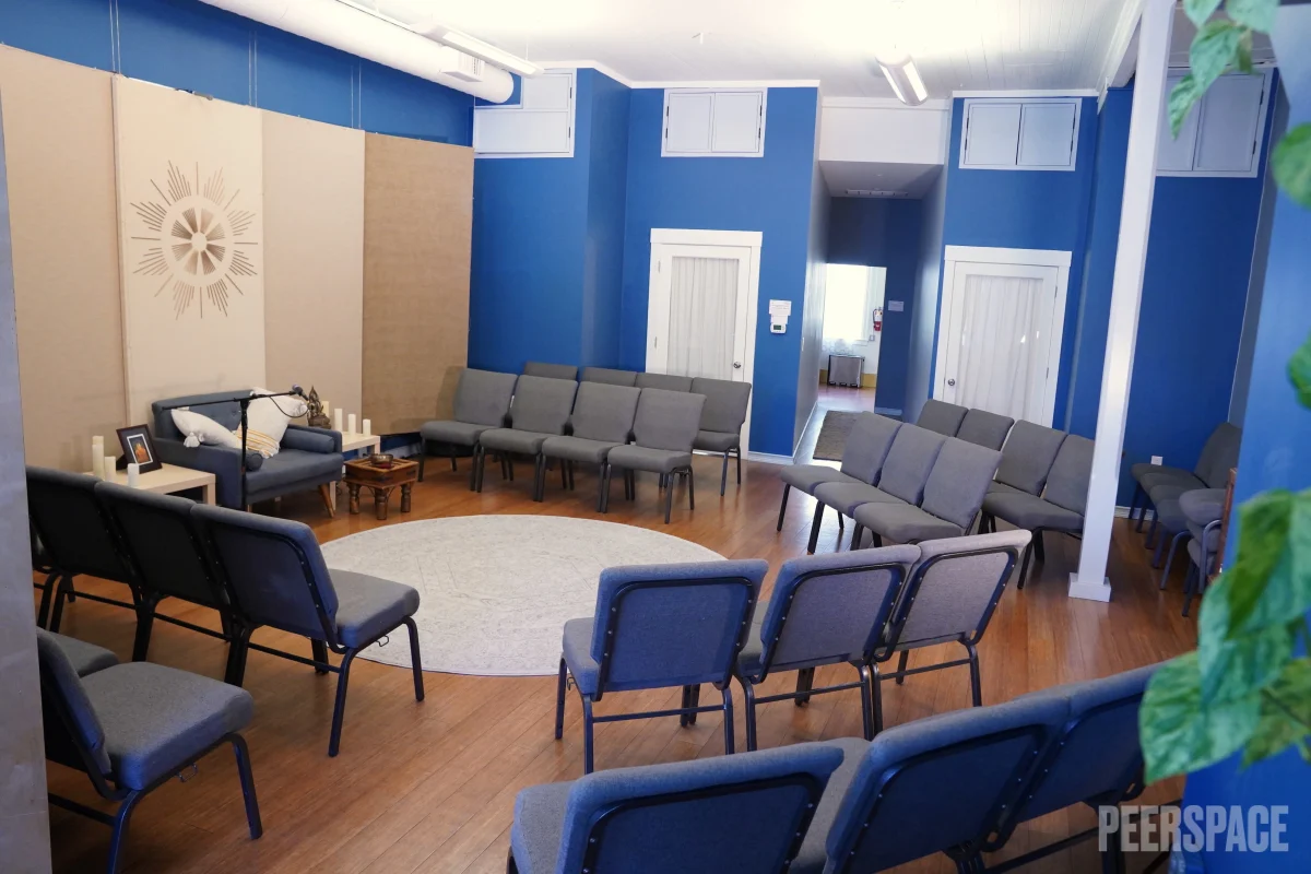 Bright interior room at the San Francisco Dharma Collective with blue walls, wood floors, and chairs set in a circle for group gatherings.