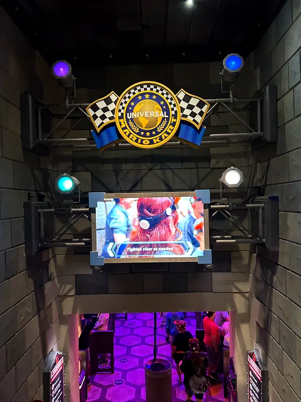 Universal Mario Kart sign and visor-instruction screen in the Mario Kart: Bowser's Challenge queue at Epic Universe