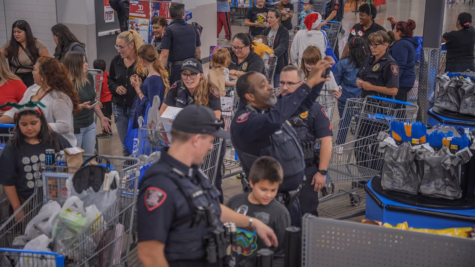 A busy store scene with multiple shoppers and police officers, surrounded by shopping carts filled with various items.
