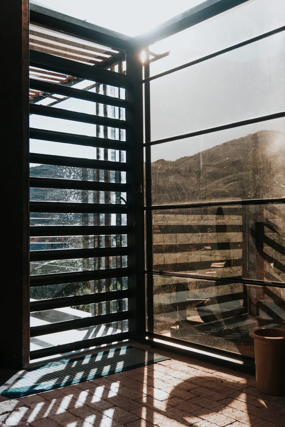 Ventana con persianas de listones de madera y vista a la montaña.