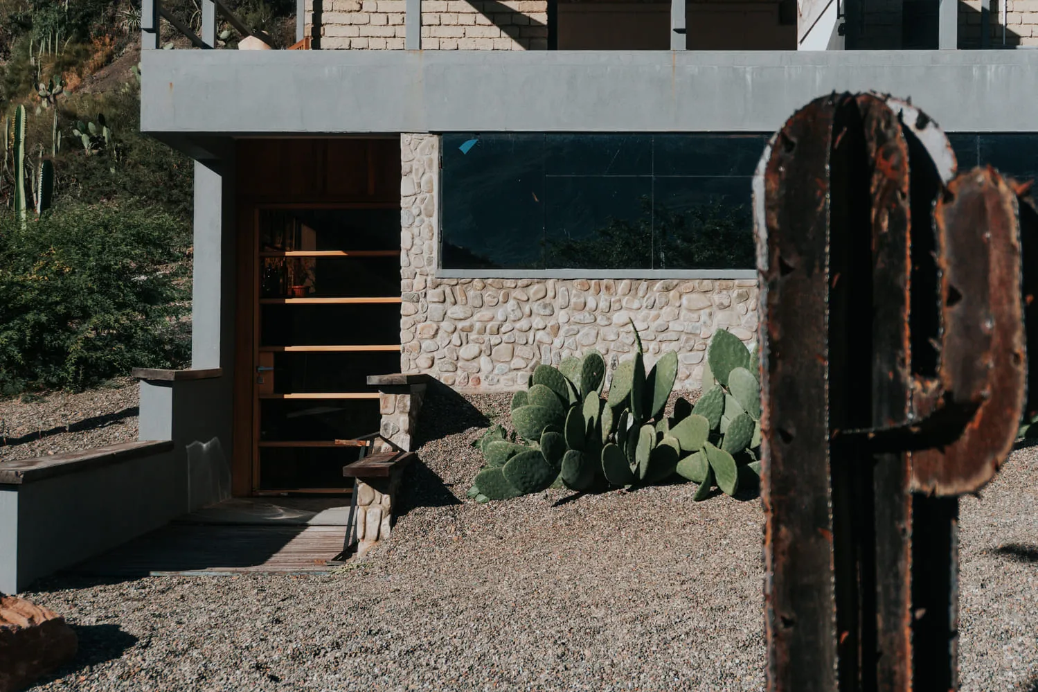 Muro de piedra con cactus y una ventana alargada.