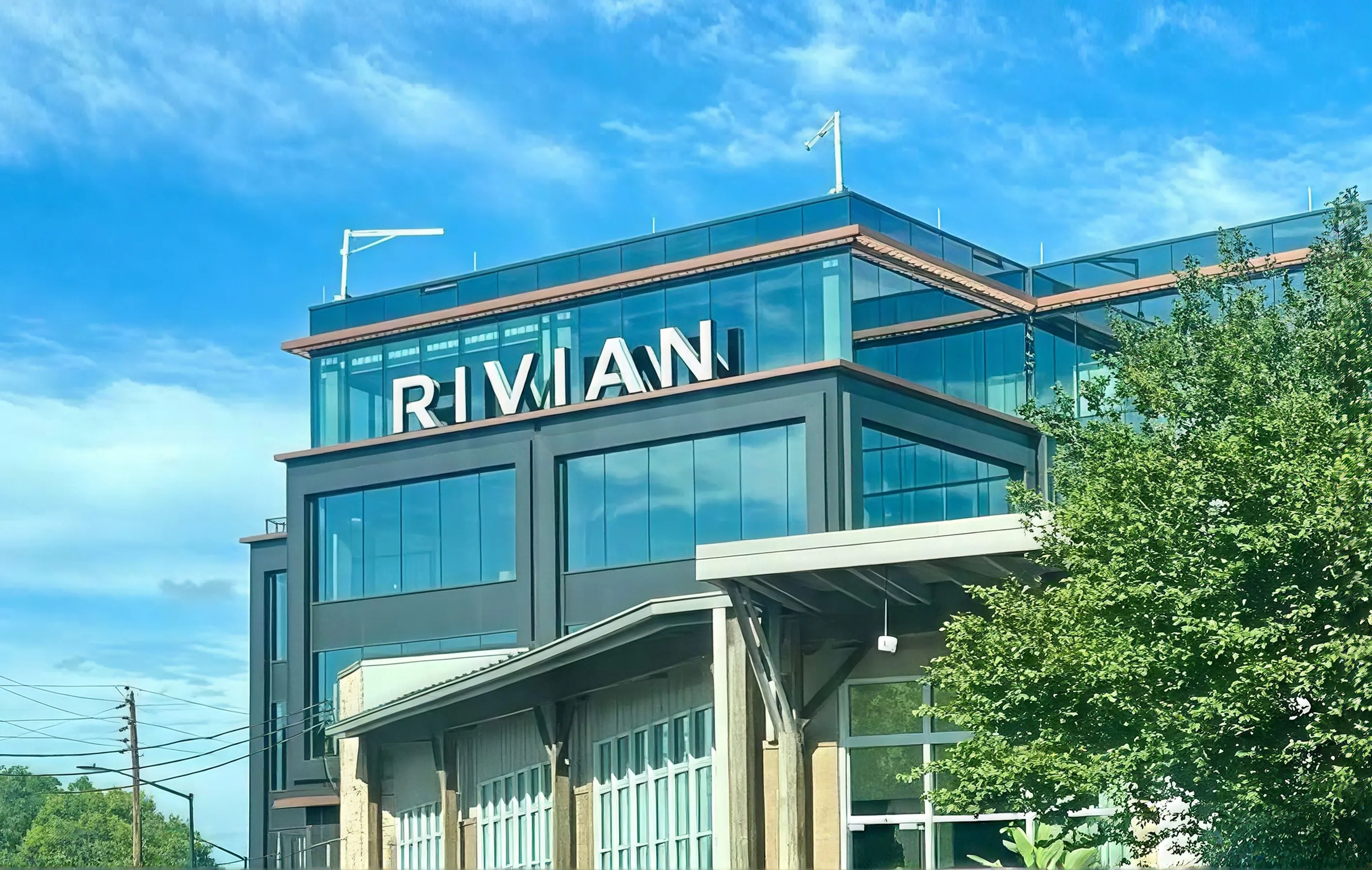 Rivian's offices under a Navigation-blue sky, the glass facade carrying the same blue