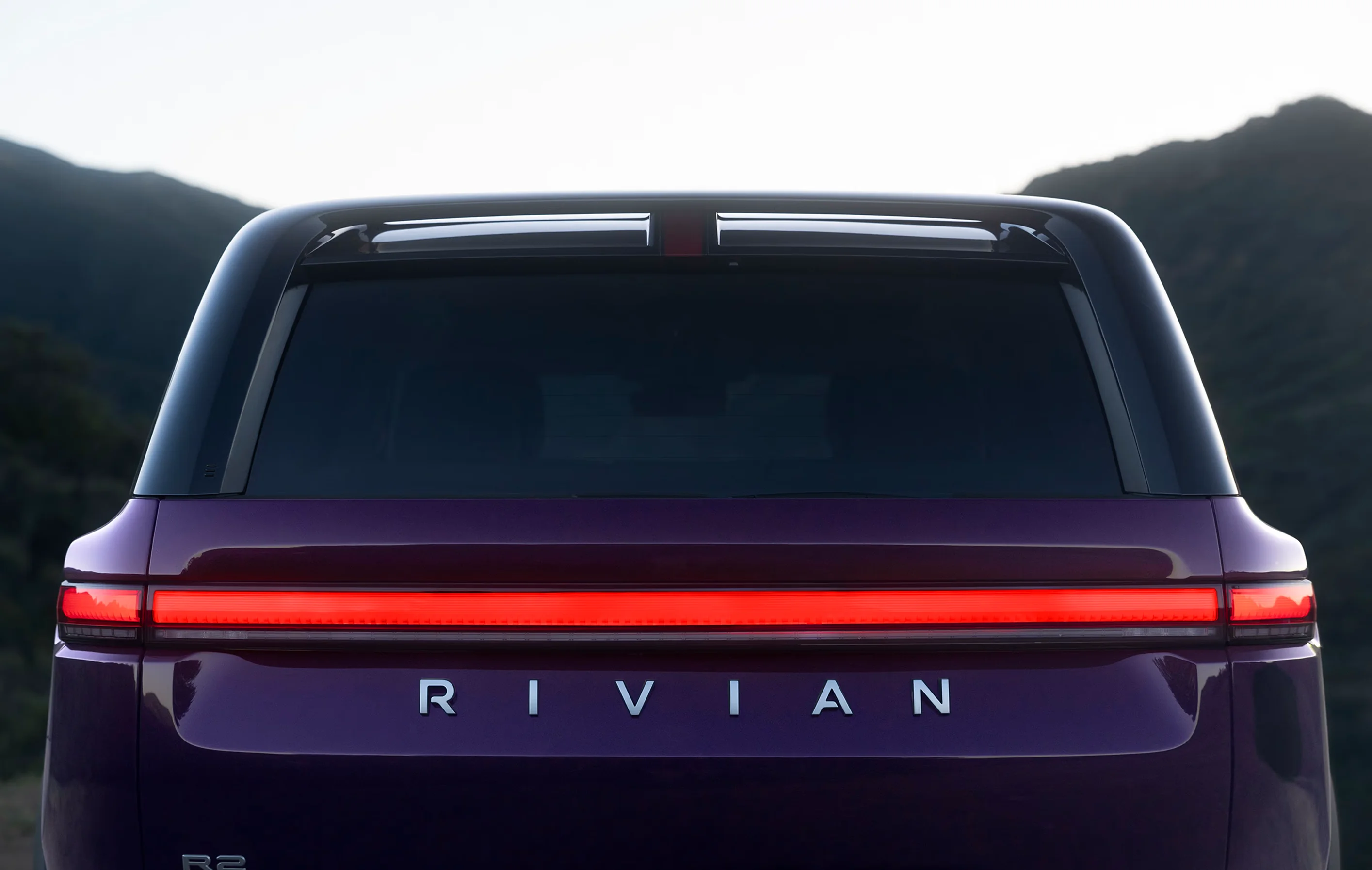 An R2 from behind, its rear light bar lit Alert red across the tailgate