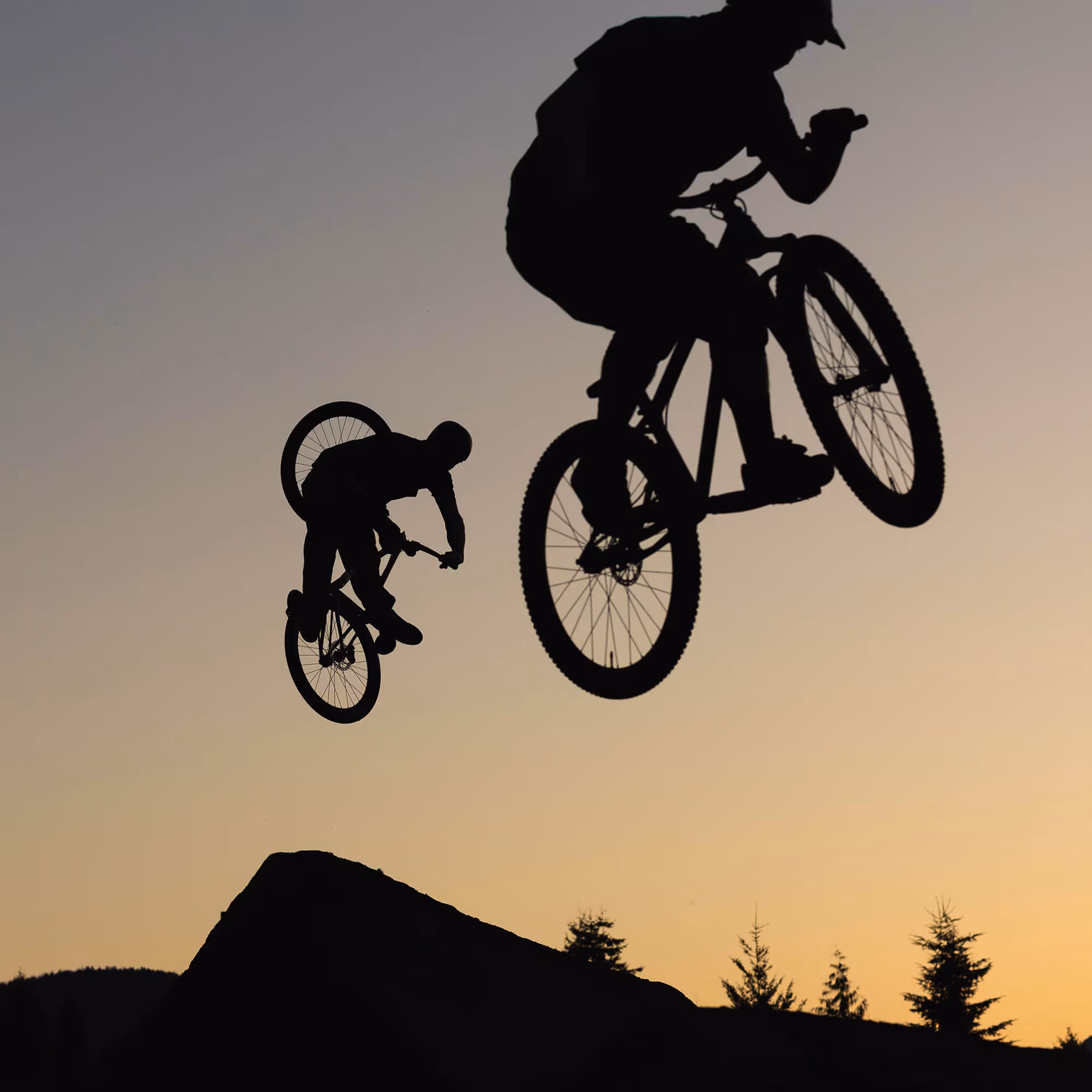 A silhouette of two dirt jump riders mid-air