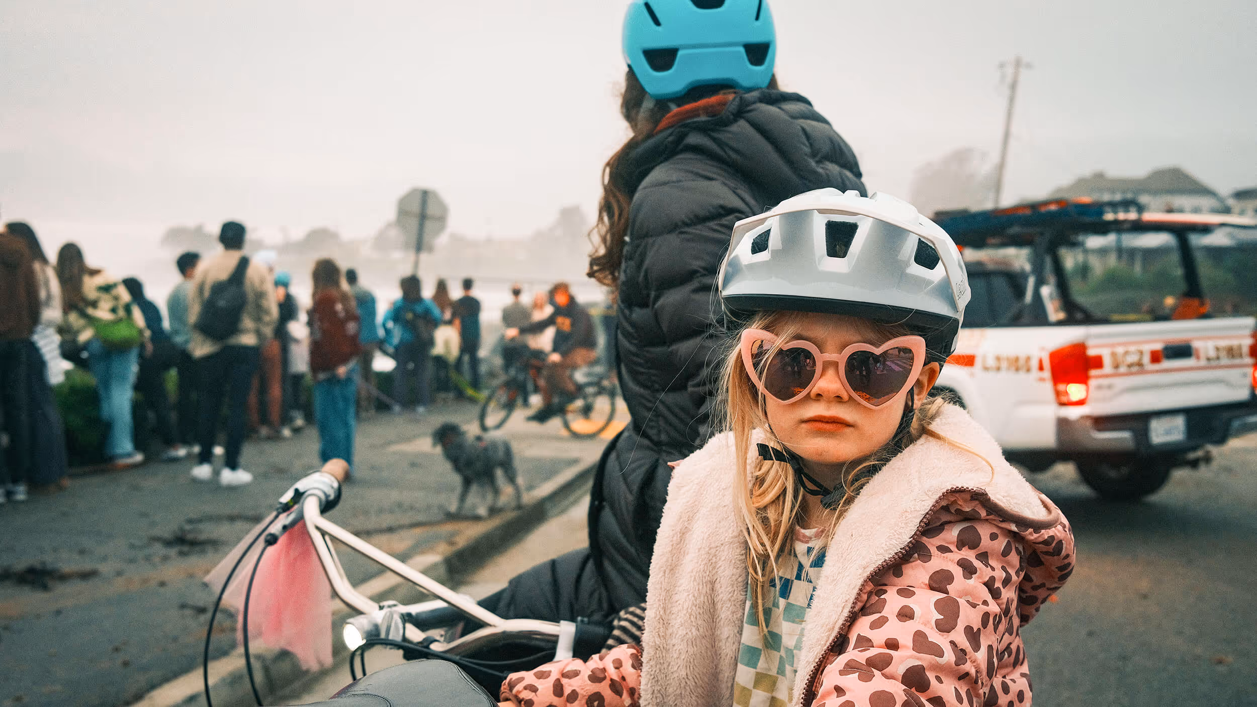 A girl in sunglasses on her bike with her mom