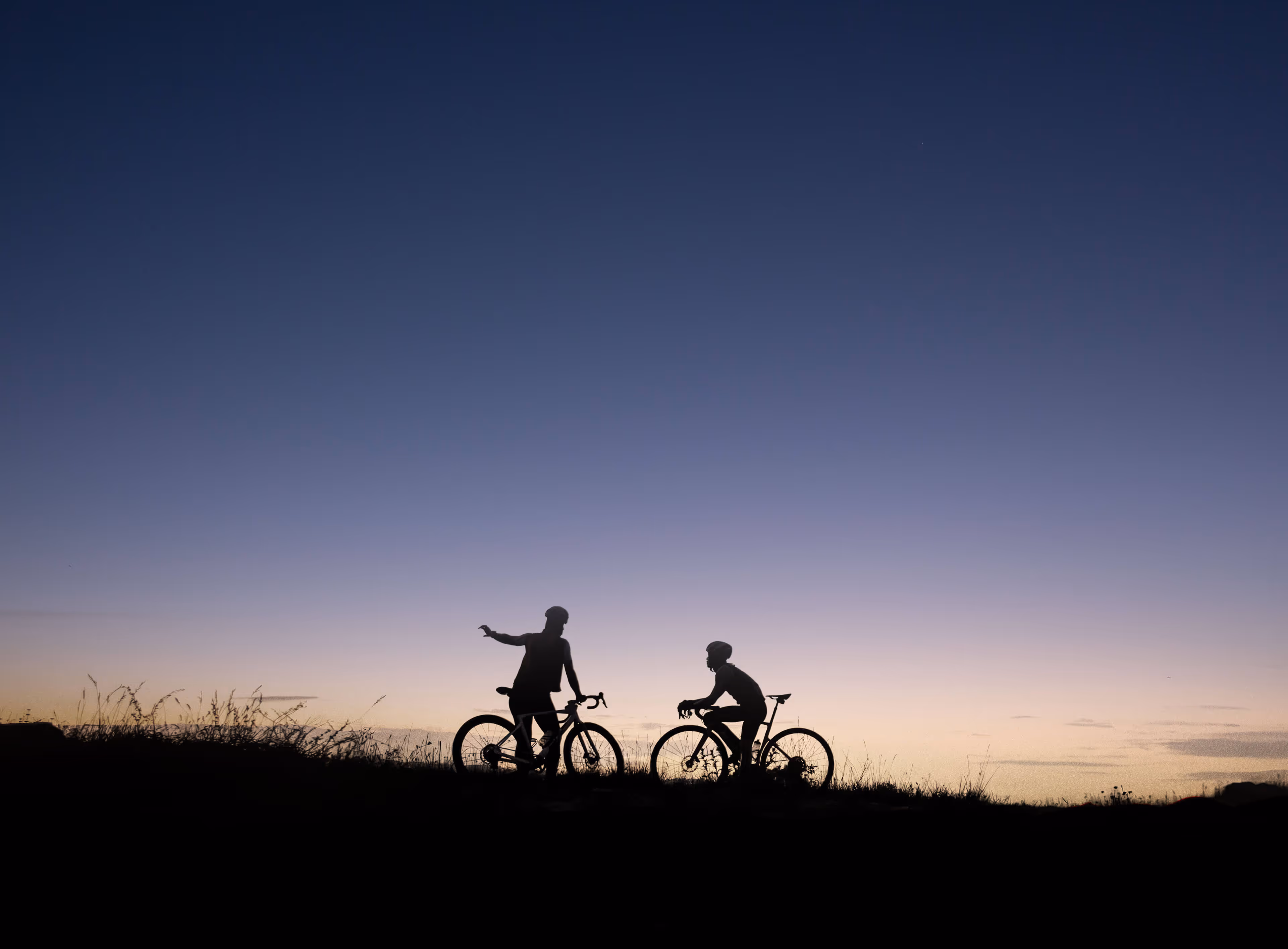 A silhouette of two resting bikers at sunset