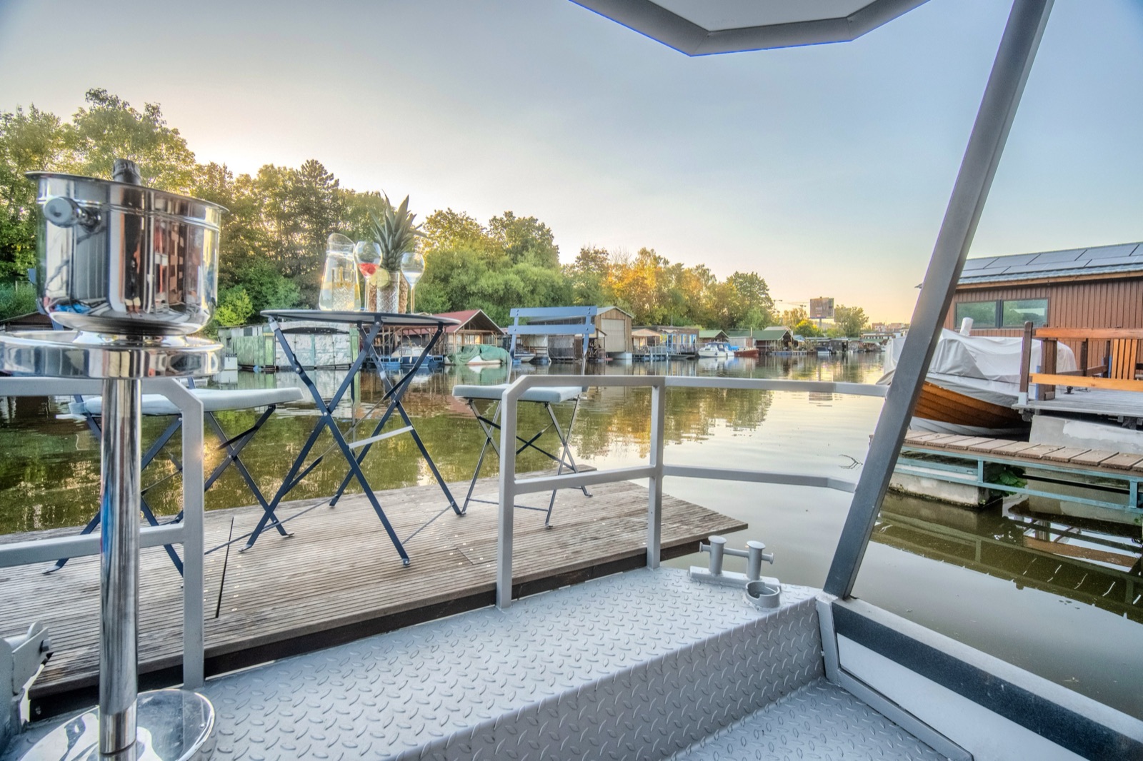 Terasa houseboatu Neptun za soumraku – stolek a židle nad hladinou Vltavy