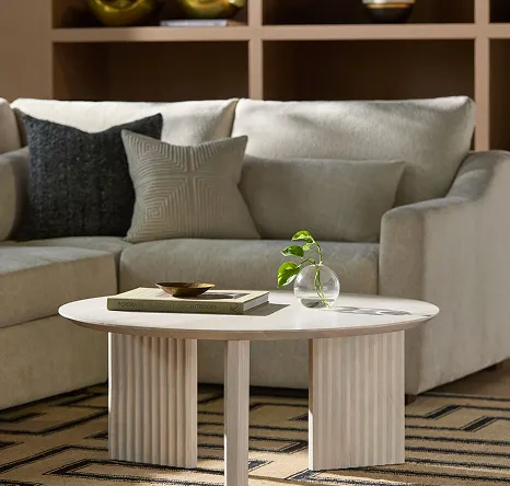 White sofa with black pillow and white pillow and white three legged coffee table