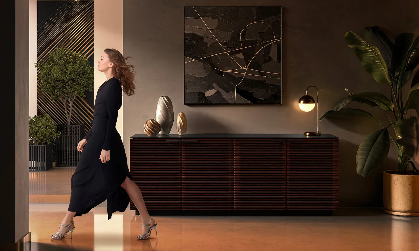 Woman walking quickly past a BDI dresser in a dimly lit room