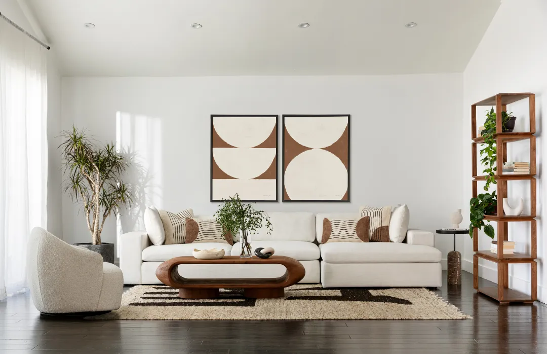 Living room collection white sofa with brown and white pillows and matching painting with white chair and wooden coffee table 