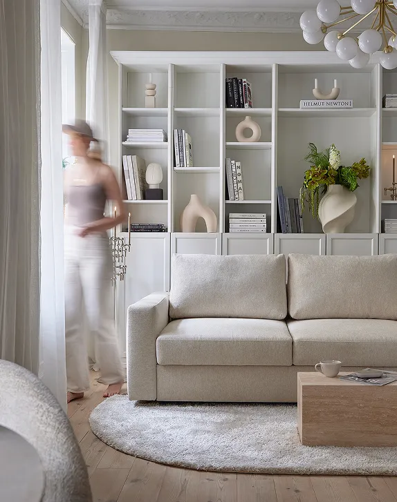 Innovation Living woman passing by a white sofa 