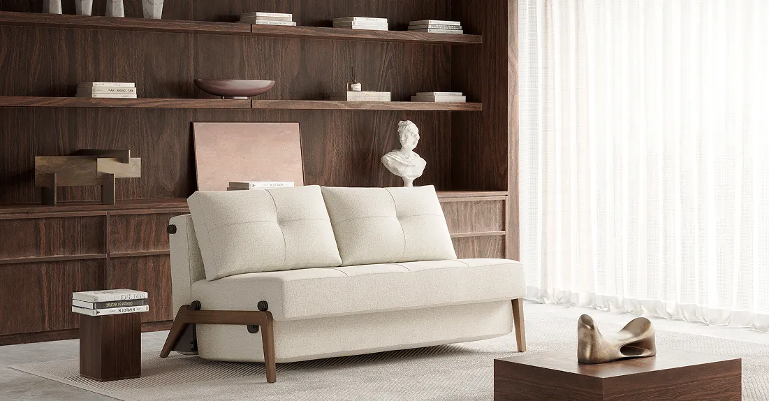 Cubed loveseat with wooden legs and a wooden bookcase in the background 