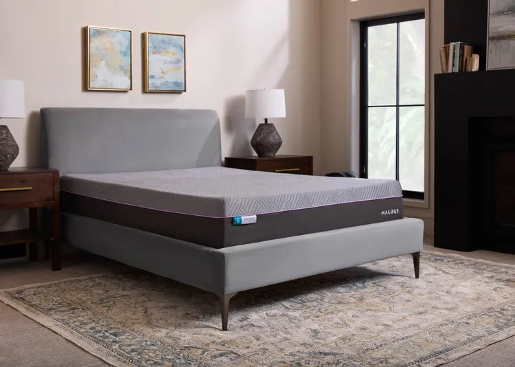 A Malouf mattress in dark grey in a simplistic bedroom setting, a medium sized window next to the bed provides bright light into the room
