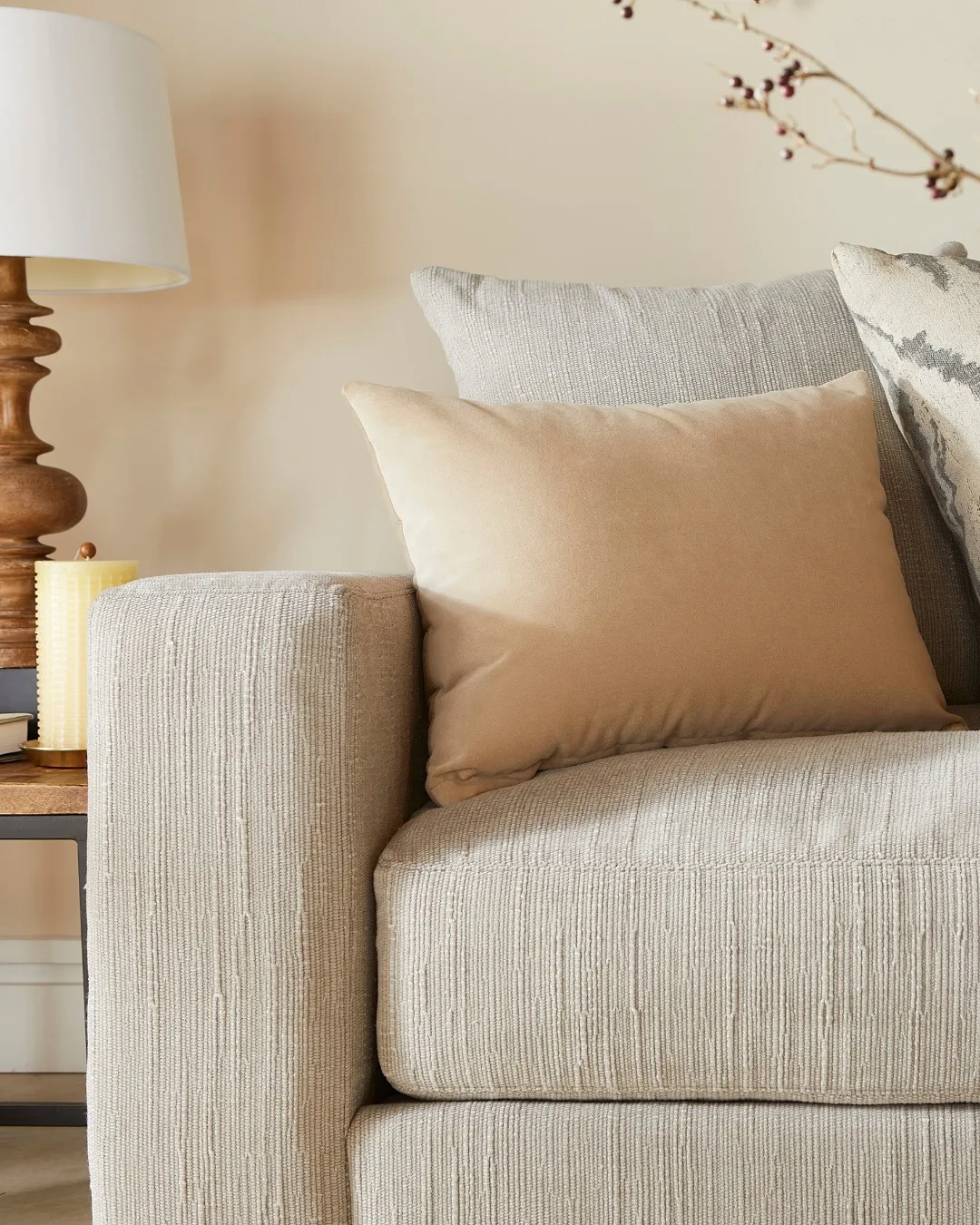 Close up of white sofa arm and light orange square pillow by Jonathan Louis