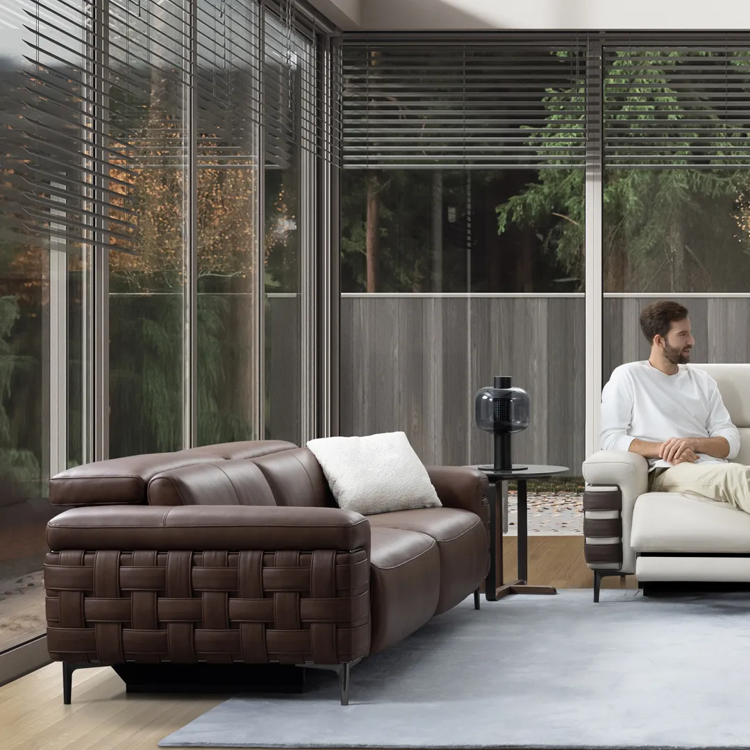 A dark brown leather sofa with a white pillow 