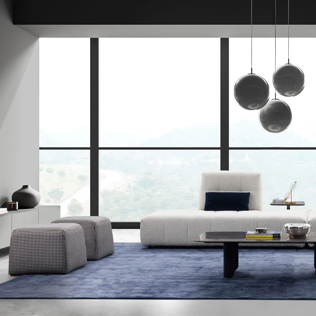 Living room set with white sofa and two grey ottomans, blue rug and three hanging lamps