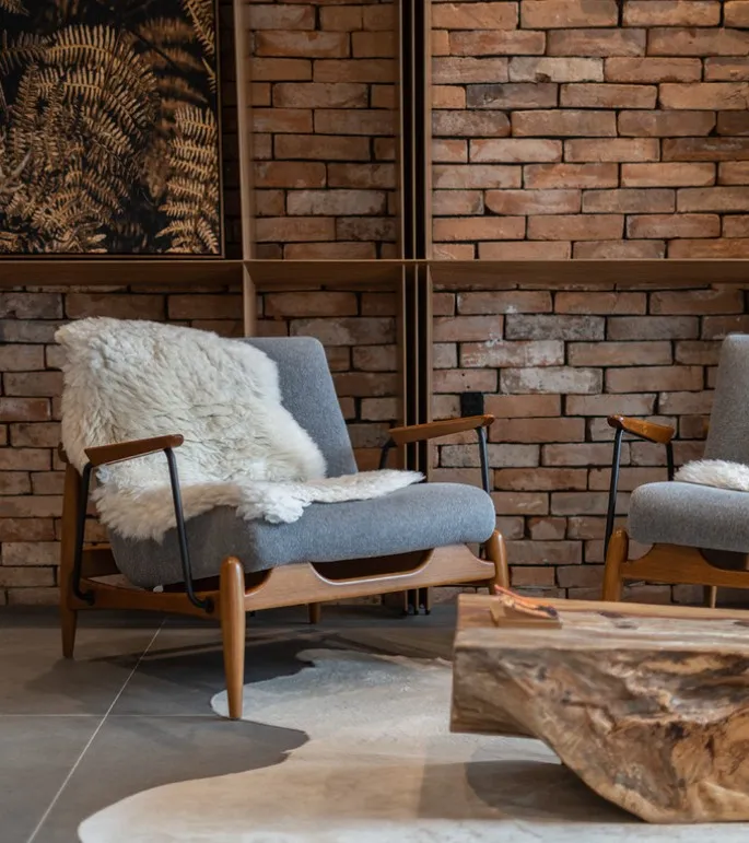 uultis grey chair with white blanket and brick wall backdrop