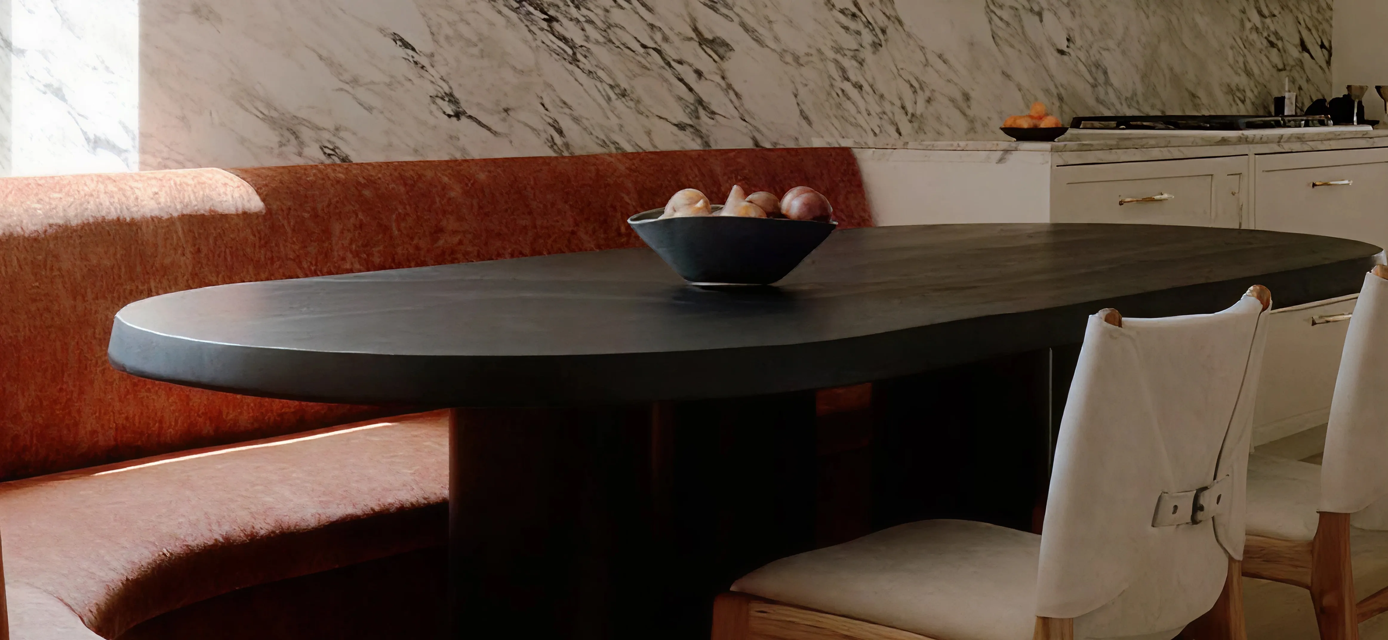 Black uultis elongated dining table with two white chairs and white wall in the background